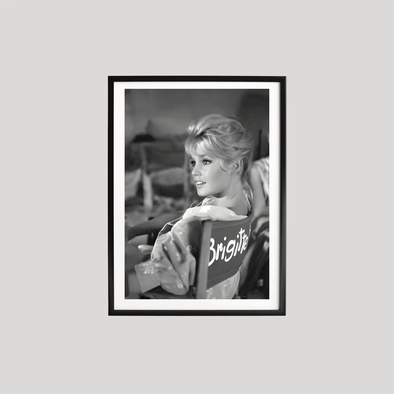 Pu&ograve; includere: Fotografia in bianco e nero incorniciata di una donna seduta su una sedia da regista. Lo schienale della sedia &egrave; etichettato "Brigitte" in scrittura bianca. La donna guarda di lato, con i capelli raccolti in uno chignon.