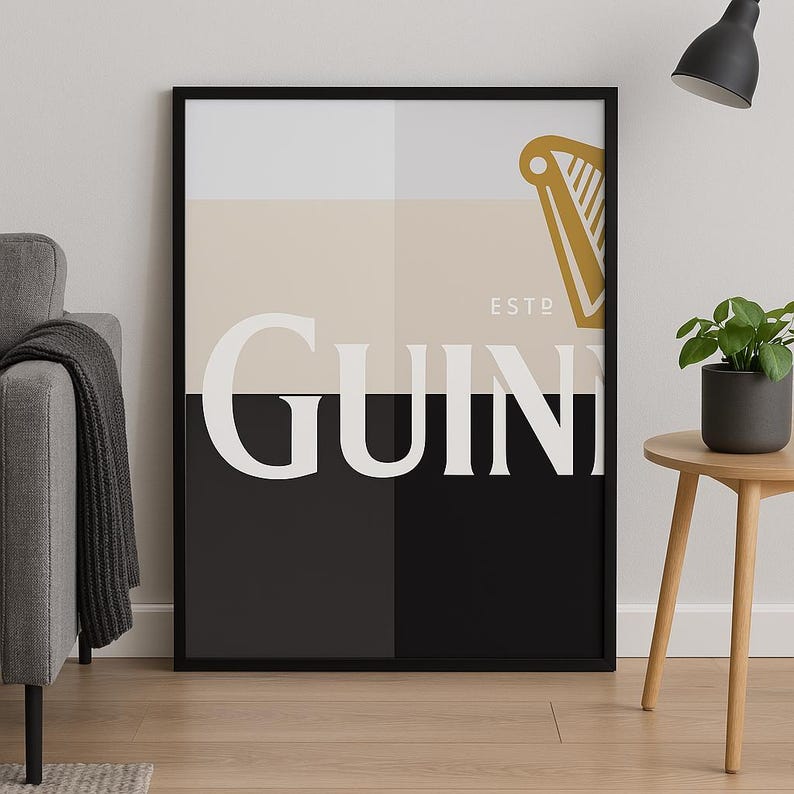 May include: Black and white poster with the word "GUINNESS" in white letters and a gold harp logo with the text "ESTD" above it. The poster has a black frame.