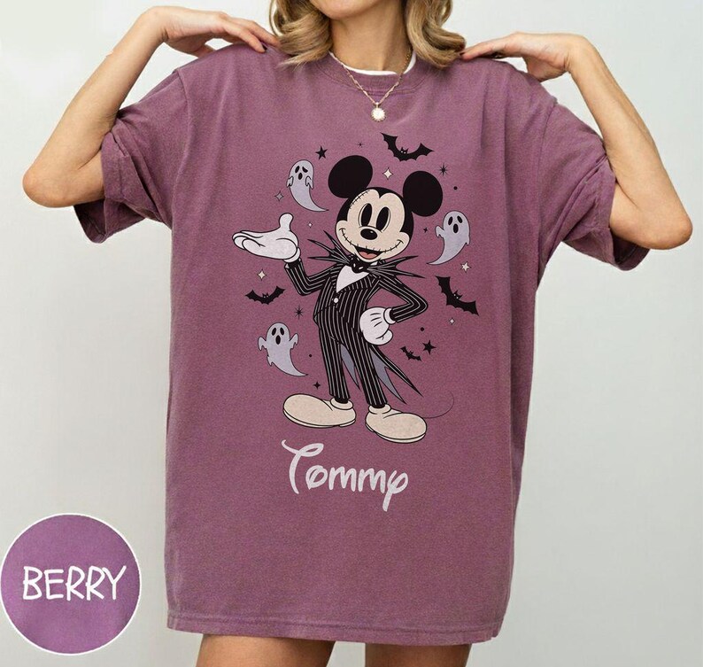 May include: A berry-colored crewneck t-shirt featuring a graphic of Mickey Mouse dressed in a pinstriped suit, surrounded by small ghosts, bats, and stars. The name Tommy is printed in white script below the character. The fabric has a vintage wash.