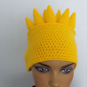 Puede incluir: Un gorro de crochet amarillo con una parte superior puntiaguda, que se asemeja al cabello de un personaje de dibujos animados.