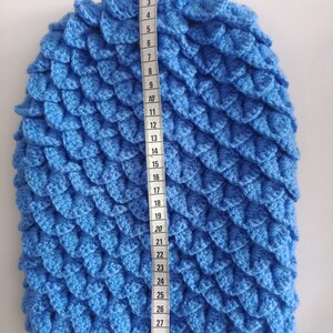 May include: A blue crocheted hat with a scale pattern, measured to be 29 inches in length.