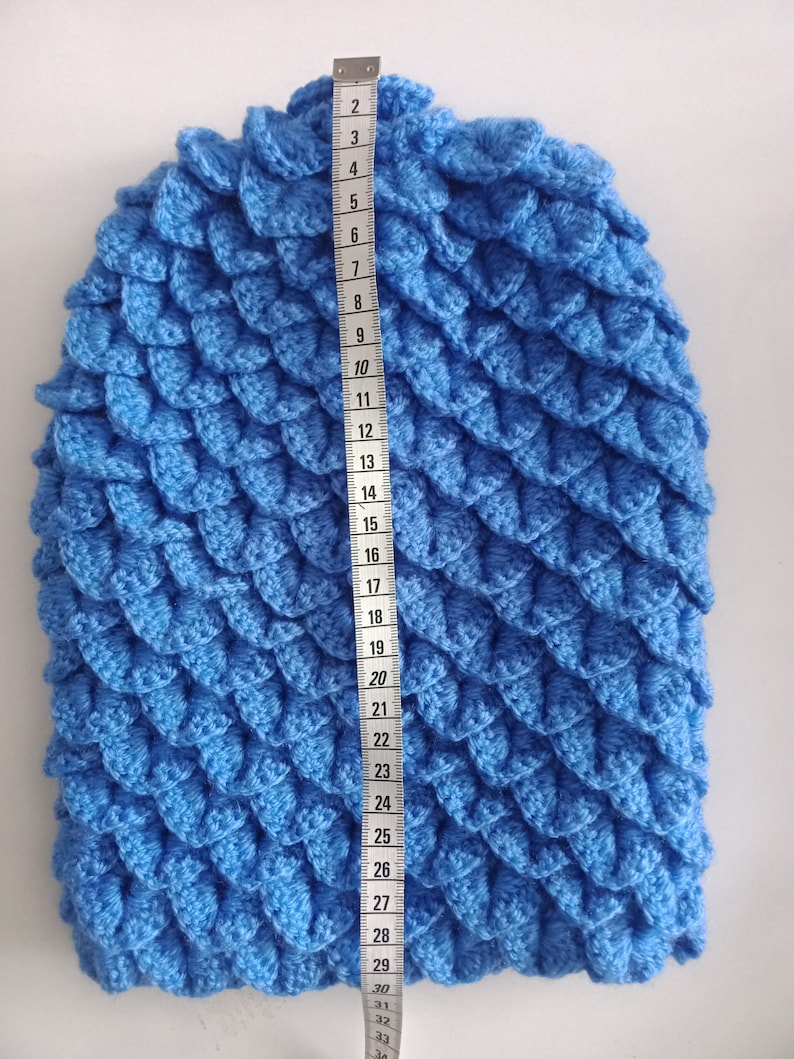 May include: A blue crocheted hat with a scale pattern, measured to be 29 inches in length.