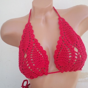 May include: Red crocheted bikini top with a halter style and a delicate, lacy design.