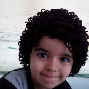 May include: A young person with brown curly hair wearing a gray and black shirt.