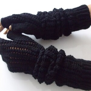 Peut inclure: Gants sans doigts noirs avec un motif tricoté. Les gants ont un long poignet qui peut être rabattu.