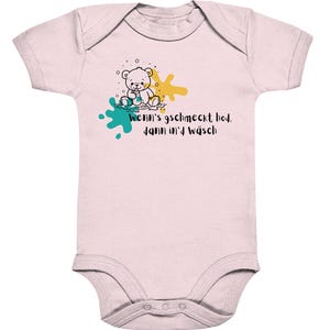 Könnte beinhalten: Hellrosa Baby-Body mit einer Illustration eines Teddybären. Der Bär hält ein Getränk, mit türkisfarbenen und gelben Farbspritzern. Der Text auf dem Body lautet "Wenn's gschmeckt hod, dann in'd Wäsch."