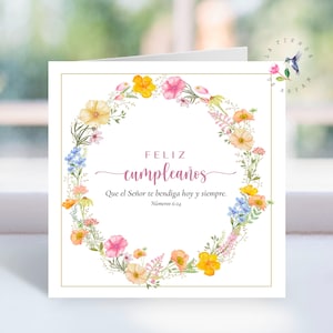 Peut inclure: Carte de vœux carrée avec une couronne florale. La couronne est composée de fleurs aquarelles jaunes, roses, oranges et bleues. Le texte en espagnol dit "Feliz cumpleaños" et une citation biblique.