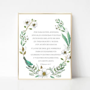 May include: A framed print with a gold border, displaying a floral wreath with white flowers, green leaves, and a teal bird. The Spanish text reads "Por nada estéis afanosos..." within the wreath.