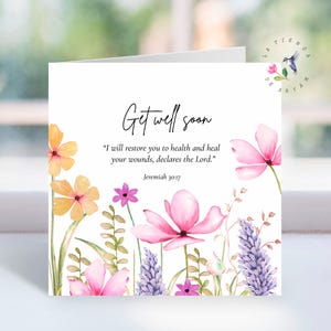 Peut inclure: Une carte de vœux blanche avec l'inscription "Get well soon" en écriture élégante. La carte présente des illustrations à l'aquarelle de fleurs roses, oranges et violettes avec du feuillage vert. Le texte "Je vous rétablirai la santé et je guérirai vos blessures, déclare le Seigneur." est également inclus.