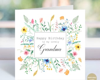 May include: A white birthday card with a floral wreath design. The card features the text "Happy Birthday to my lovely Grandma" in a black frame. The wreath includes yellow, pink, blue, and orange flowers with green leaves.
