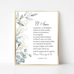 May include: A framed print with the text "El Amor" in elegant script, featuring a poem in Spanish. The artwork is adorned with watercolor-style botanical elements in shades of green, gold, and white, set against a white background.