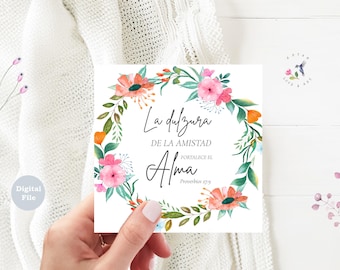 May include: A square digital file with a floral wreath design. The wreath features pink and orange flowers with green leaves. Text in Spanish reads "La dulzura de la amistad fortalece el Alma" and "Proverbios 27:9". A small logo with a hummingbird is in the upper right corner.