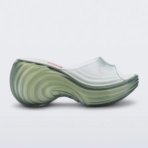 Könnte beinhalten: Transparente Keilsandalen mit einer wirbelnden, grün getönten Sohle und einem transparenten Obermaterial. Die Sandalen haben einen Plateauabsatz und ein Slip-on-Design. Das Wort "DIESEL" ist rot auf der Innensohle aufgedruckt.