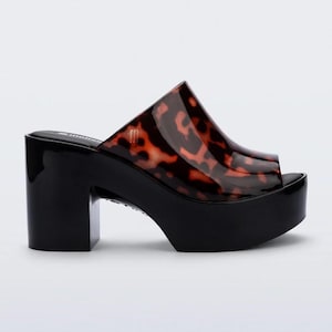May include: Black platform sandals with a tortoiseshell-patterned upper. The open-toe design features a thick, block heel and a platform sole. The sandals have a glossy finish and are suitable for various occasions.