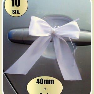 Puede incluir: Diez lazos de puerta de coche de satén blanco con una perla en el centro. Cada lazo mide 40 mm de ancho.