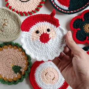 May include: A collection of handmade crochet Christmas coasters. Designs include a snowman, Santa Claus, and other festive patterns in red, white, green, and beige. These coasters are perfect for holiday decor.