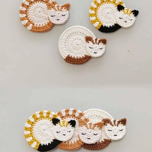 May include: Set of four crocheted cat-shaped coasters in white, brown, and yellow. The coasters are designed to look like sleeping cats with closed eyes.
