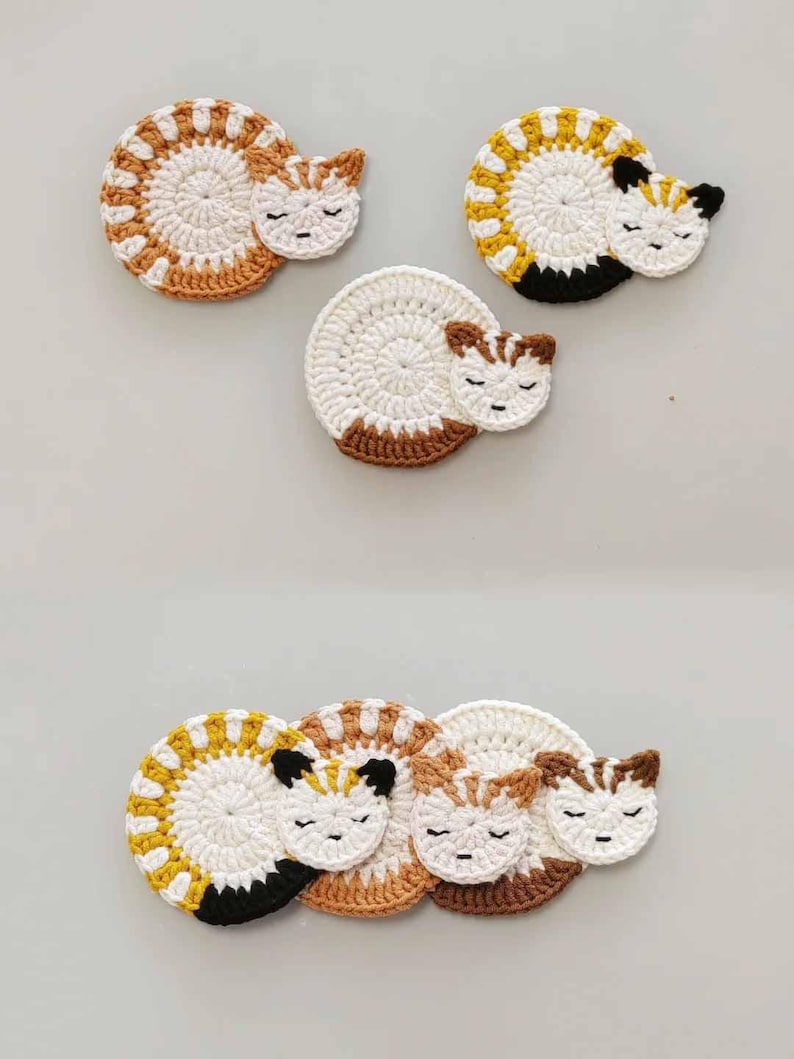 May include: Set of four crocheted cat-shaped coasters in white, brown, and yellow. The coasters are designed to look like sleeping cats with closed eyes.