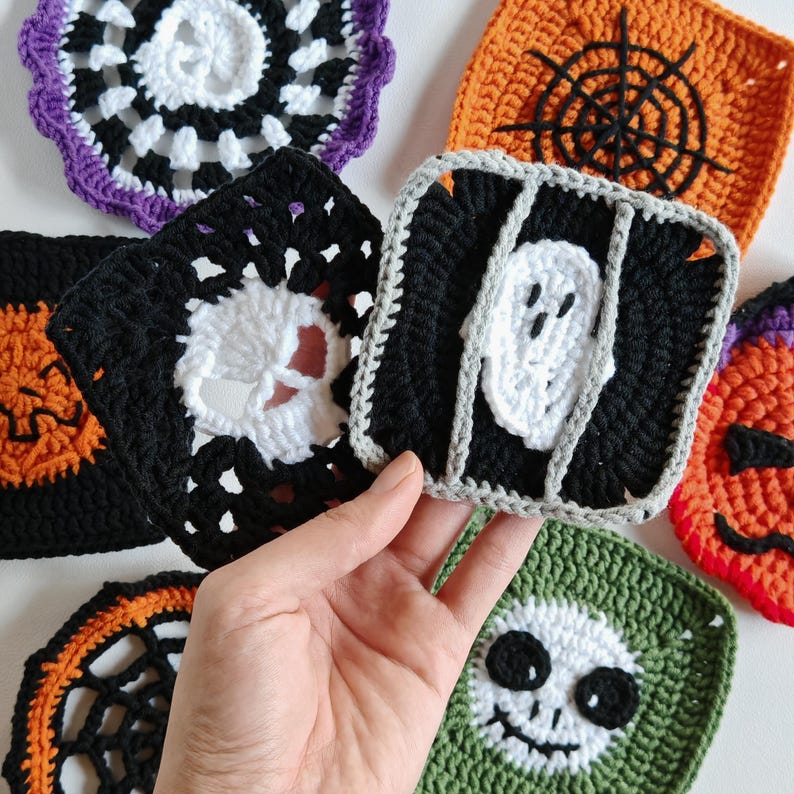 May include: A collection of colorful, handmade crochet Halloween coasters. Designs include a spiderweb, a skull, a ghost, and a jack-o'-lantern. The coasters are square and round, with a variety of colors including black, orange, white, green, and purple.