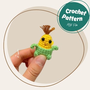 以下が含まれることがあります： かわいいトウモロコシの編みぐるみおもちゃを作るための、かぎ針編みのパターンPDFファイルです。トウモロコシは黄色で、緑色の皮と茶色の髪をしています。黒い目と笑顔の口をしています。