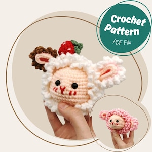 May include: A crocheted sheep toy with a strawberry and chocolate accents. The sheep has a white fluffy wool, pink face, and black eyes. The image includes the text "Crochet Pattern PDF File".