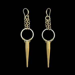 May include: A pair of gold earrings with a chain, a circle, and a pointed spike.