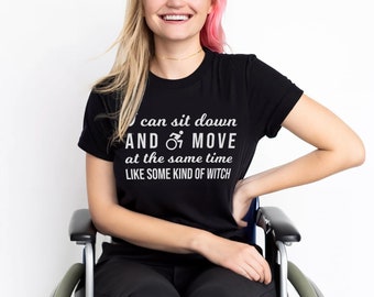 May include: A woman wearing a black t-shirt with the text "I can sit down AND MOVE at the same time LIKE SOME KIND OF WITCH" in white lettering. She is sitting in a wheelchair.