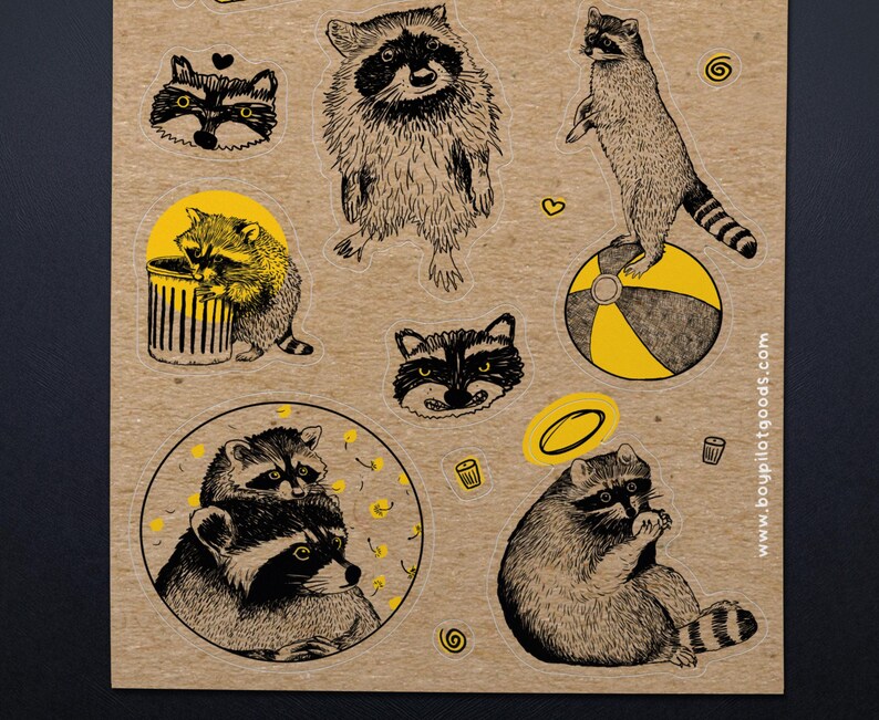 Puede incluir: Una hoja de pegatinas de mapaches en varias poses, con detalles en amarillo. Las pegatinas muestran mapaches de pie, sentados y asom&aacute;ndose a un cubo de basura. El fondo es de color marr&oacute;n claro.