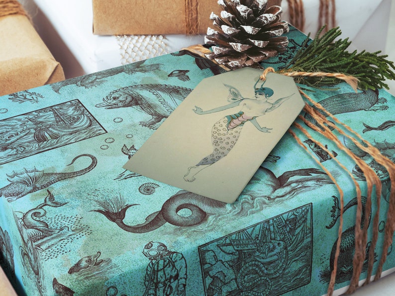 May include: Gift-wrapped present with teal wrapping paper featuring illustrations of sea creatures and ships. A mermaid tag is attached with twine. A pine cone and greenery add a festive touch.