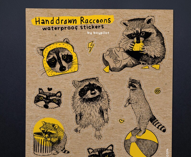 Puede incluir: Una hoja de pegatinas impermeables de mapaches dibujadas a mano. Las pegatinas presentan varias ilustraciones de mapaches, incluyendo uno con un disfraz de pan y otro comiendo patatas fritas. El texto "Handdrawn Raccoons" y "waterproof stickers" es visible.