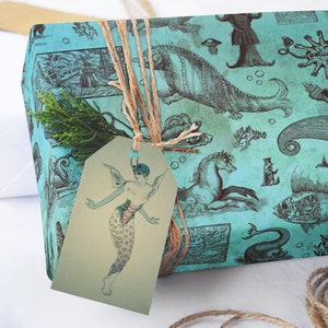 May include: A wrapped gift with teal paper featuring vintage illustrations of sea creatures and nautical elements. The gift is tied with twine and has a tag with a mermaid illustration. A sprig of greenery adds a natural touch.