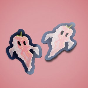 May include: Two pink ghost pepper stickers on a pink background. The stickers are shaped like ghosts and have a black outline.
