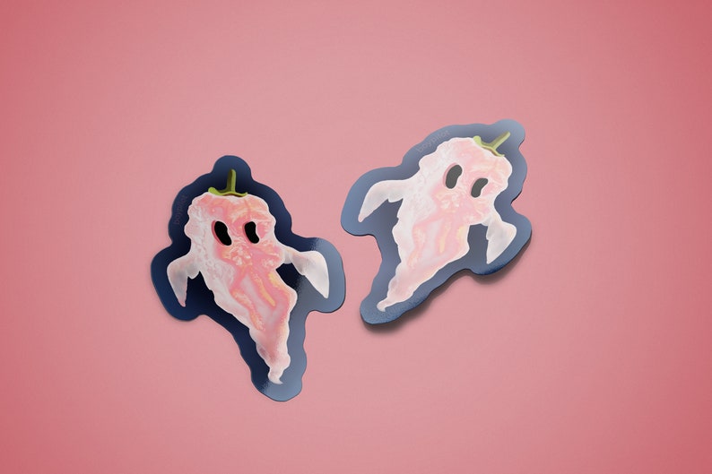 May include: Two pink ghost pepper stickers on a pink background. The stickers are shaped like ghosts and have a black outline.