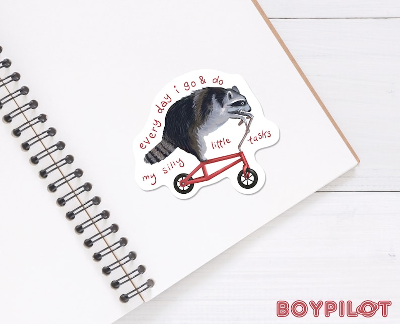Peut inclure: Autocollant repr&eacute;sentant un raton laveur sur un tricycle rouge. Le raton laveur est noir, gris et blanc. Le texte sur l'autocollant dit : "every day I go & do my silly little tasks."
