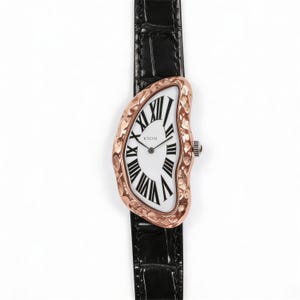 May include: A unique wristwatch with a distorted, melting-style face. The watch features a white face with black Roman numerals and a rose gold-colored bezel. The black leather band adds a classic touch. The watch is labeled "KYOSI".