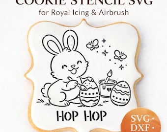 Op de afbeelding: Een cookie stencil SVG voor royal icing en airbrush. Het ontwerp toont een konijn dat paaseieren schildert, met de tekst "HOP HOP". Bevat SVG-, DXF- en PNG-bestandsformaten. De koek is wit met een goudbruine rand.