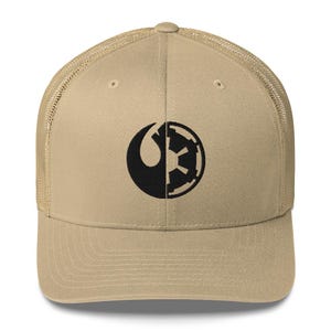 Könnte beinhalten: Beige Trucker-Cap mit einem schwarzen Grafikdesign, das zwischen einer Mondsichel und einem segmentierten Kreis aufgeteilt ist. Die Kappe hat einen Mesh-Rücken und einen gebogenen Schirm. Ein lässiges Accessoire für Fans einer beliebten Science-Fiction-Franchise.