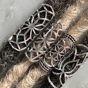 May include: Three silver dreadlock beads with a geometric design. The beads are stacked on top of each other and are made of a metal with a shiny finish.