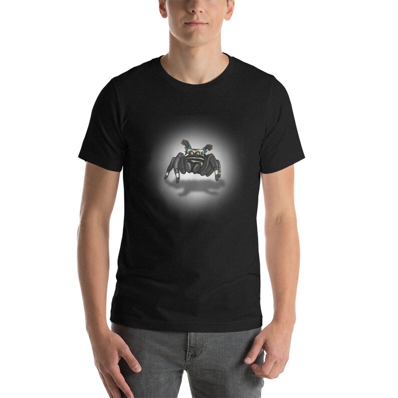 Może przedstawiać: Czarny t-shirt z kresk&oacute;wkowym obrazkiem skaczącego pająka z niebieskimi i ż&oacute;łtymi akcentami.
