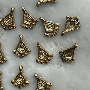 May include: A group of 12 gold-toned metal charms with a geometric design. Each charm has a teardrop shape with a small loop at the top for attaching to a necklace or bracelet.