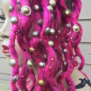 May include: Pink synthetic dreadlocks with silver and gold beads and charms.