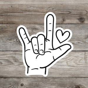 May include: A black and white illustration of a hand making the American Sign Language sign for "I love you". A small heart is drawn next to the hand.