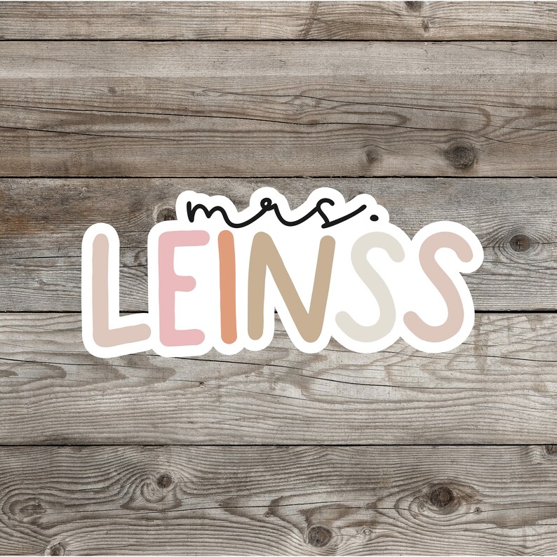 Pu&ograve; includere: Un adesivo con il testo "mrs. LEINSS" in un contorno bianco. Le lettere sono di diversi colori: rosa, pesca, beige e marrone chiaro.