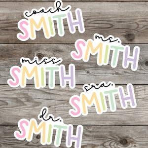 Pu&ograve; includere: Cinque adesivi colorati con la parola "SMITH" in diversi colori e caratteri. Gli adesivi hanno titoli diversi, tra cui "coach", "mrs.", "miss", "sara" e "dr."