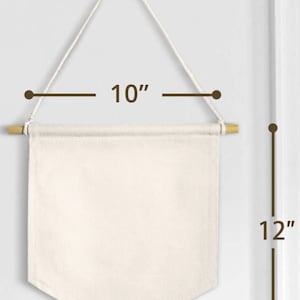 Peut inclure: Une banni&egrave;re en toile blanche avec une baguette en bois en haut et une suspension en corde. La banni&egrave;re mesure 25,4 cm de large et 30,5 cm de haut.