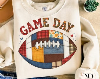 Könnte beinhalten: Cremefarbenes Sweatshirt mit dem Schriftzug "GAME DAY" in Rot und Braun. In der Mitte befindet sich ein Football-Motiv aus Patchwork-Stoff in verschiedenen Farben und Mustern. Das Sweatshirt wird mit blauen Jeans und einem braunen Hut kombiniert.