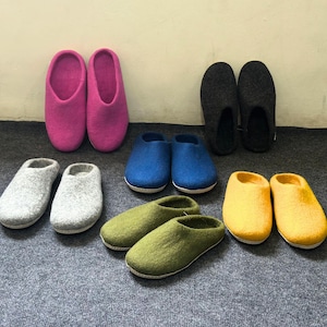 Puede incluir: Surtido de diez zapatillas de fieltro en varios colores, incluyendo rosa, gris, azul, verde y amarillo. Las zapatillas son todas planas y tienen un diseño sencillo.