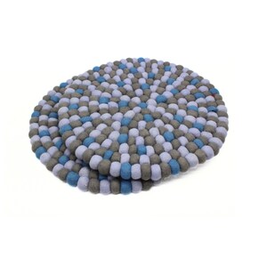 May include: Two round felt trivets. Each trivet is made of small, tightly packed felt balls in shades of blue, gray, and white. The trivets are designed to protect surfaces from heat and add a decorative touch.