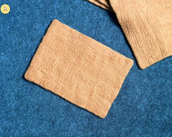 Puede incluir: Dos posavasos rectangulares de color beige con una superficie texturizada se muestran sobre un fondo azul. Los posavasos tienen un patrón de cuadrícula y parecen estar hechos de un material natural. Vista superior.