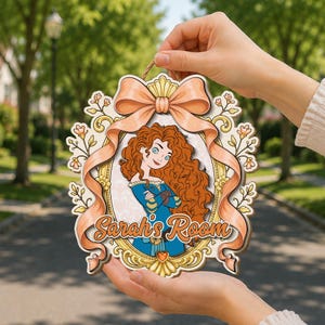 May include: A decorative wooden wall sign featuring a cartoon illustration of a character with long curly red hair in a blue dress, framed by a gold border and a large peach-colored ribbon, with the text Sarah's Room printed in orange.
